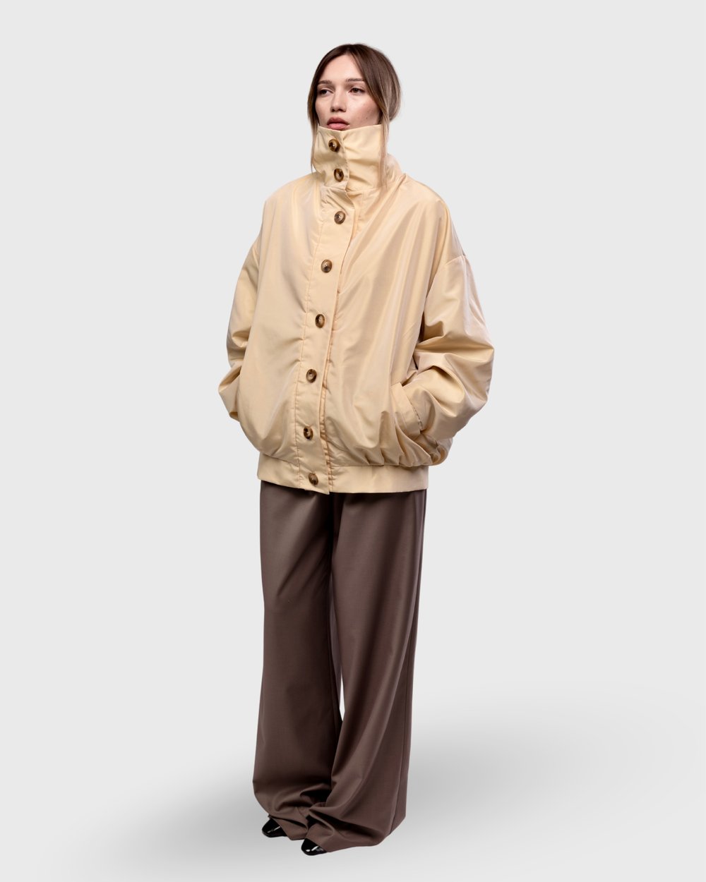 Cream bomber jacket with a high buttoned collar, front view