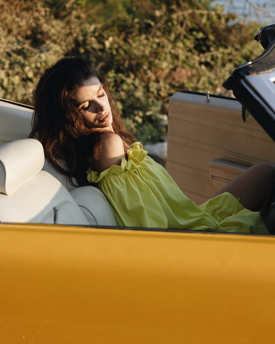 Model in the yellow TIERR set resting in the convertible