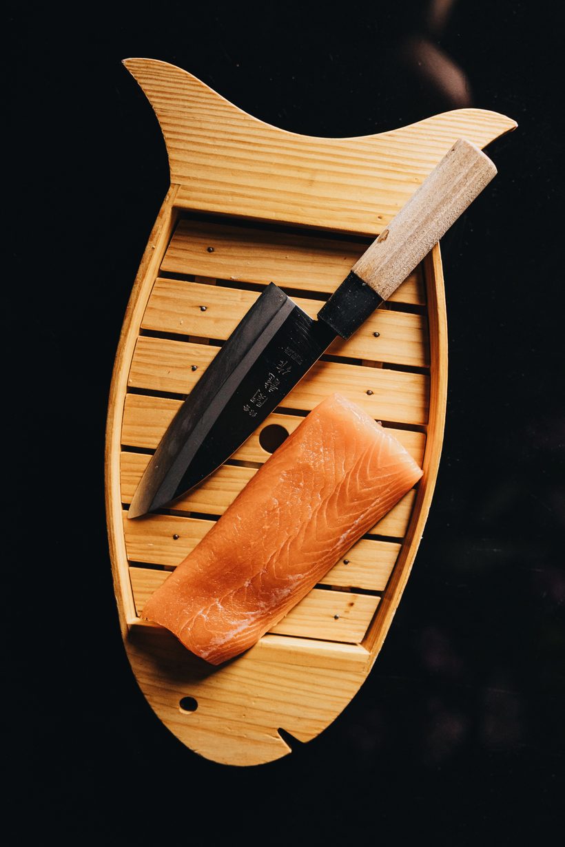 Salmon fillet and Japanese knife on a fish-shaped board
