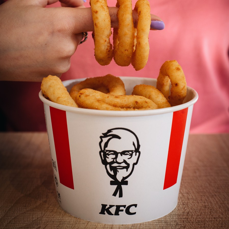 Onion rings stacked on a finger above a KFC bucket