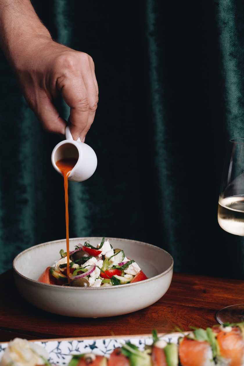 Dressing poured over a salad in front of green velvet