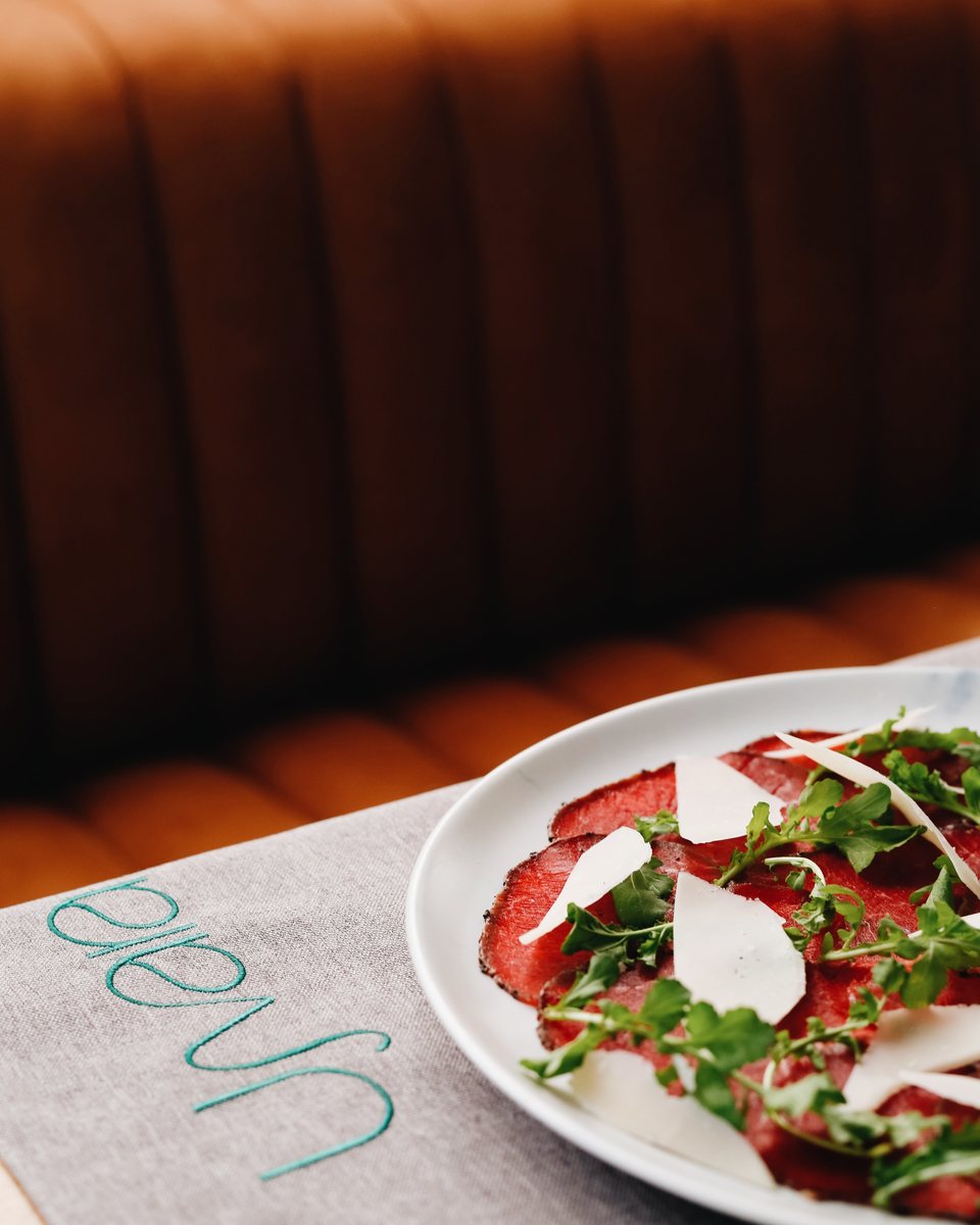 Beef carpaccio with parmesan and rocket beside an embroidered Ujvara runner