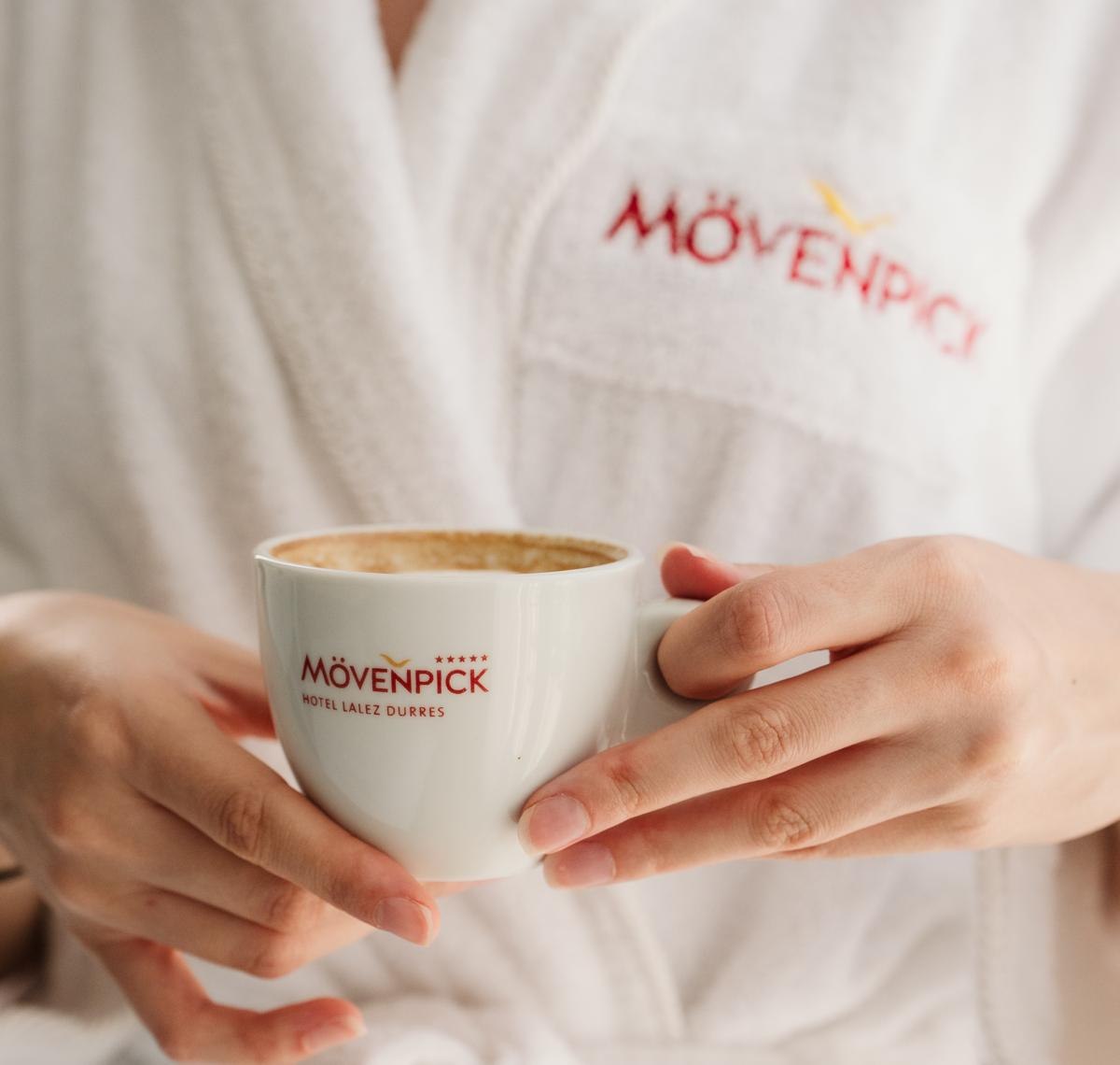 Hands holding a Movenpick Hotel Lalez Durres coffee cup