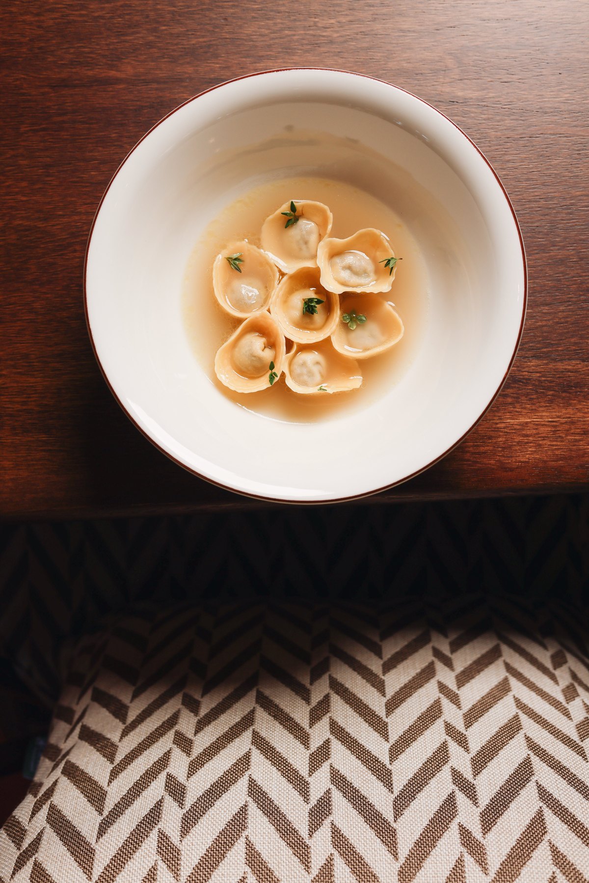 Cappellacci in broth from above on a wooden table