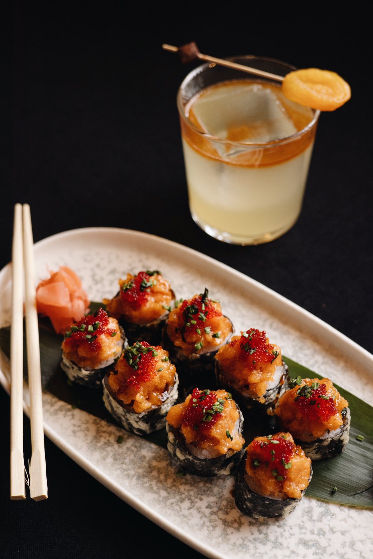 Tempura sushi rolls with chopsticks and an apricot cocktail