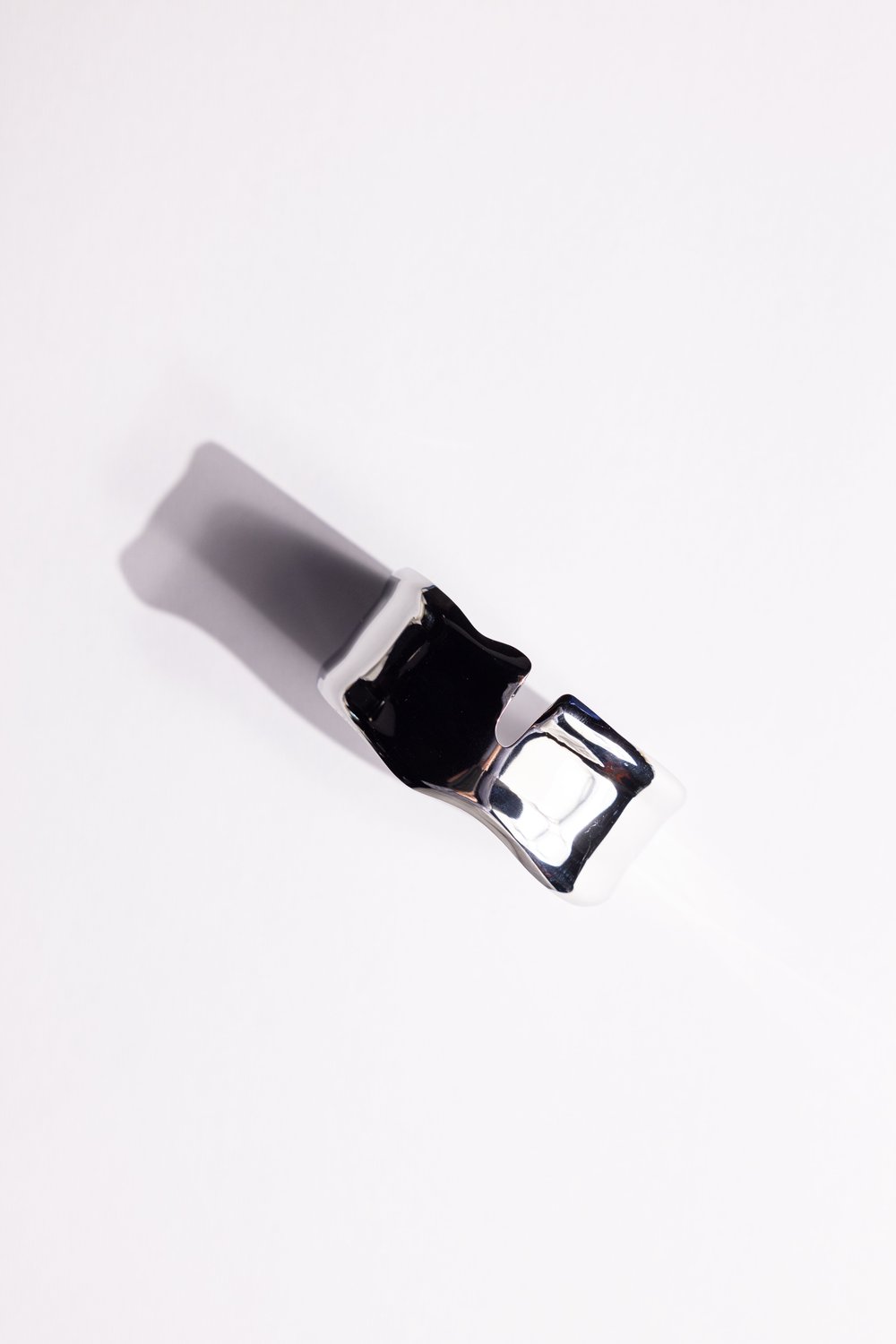 Polished silver cuff casting a long shadow on white