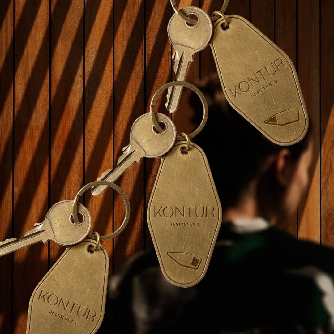 Brass Kontur Residences key tags hanging against a wooden wall