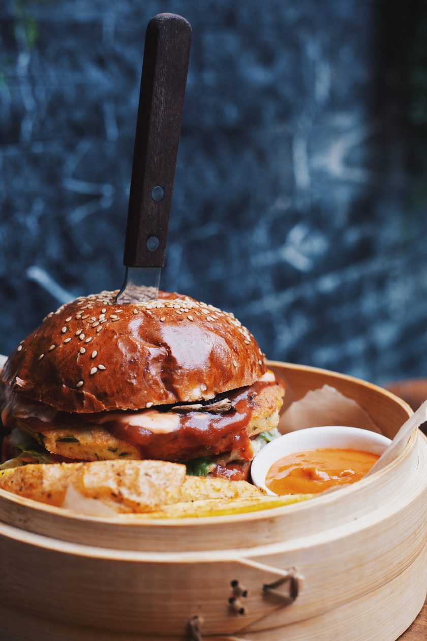 Burger with a knife through the bun in a bamboo steamer