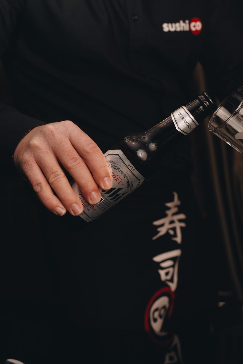 Pouring an Asahi beer in front of a Sushi Co apron