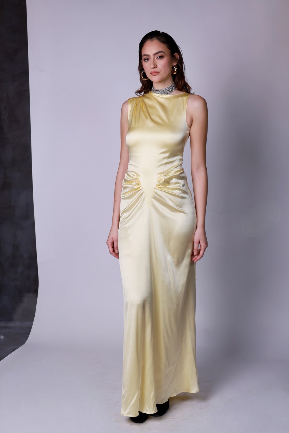 Model in a pale yellow satin dress on the studio backdrop