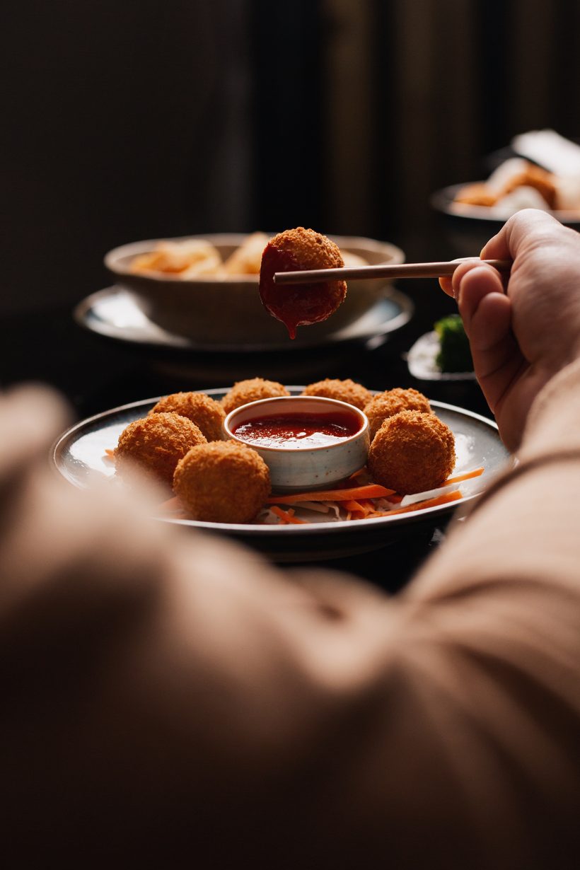 Crispy croquette dipped in sauce with chopsticks