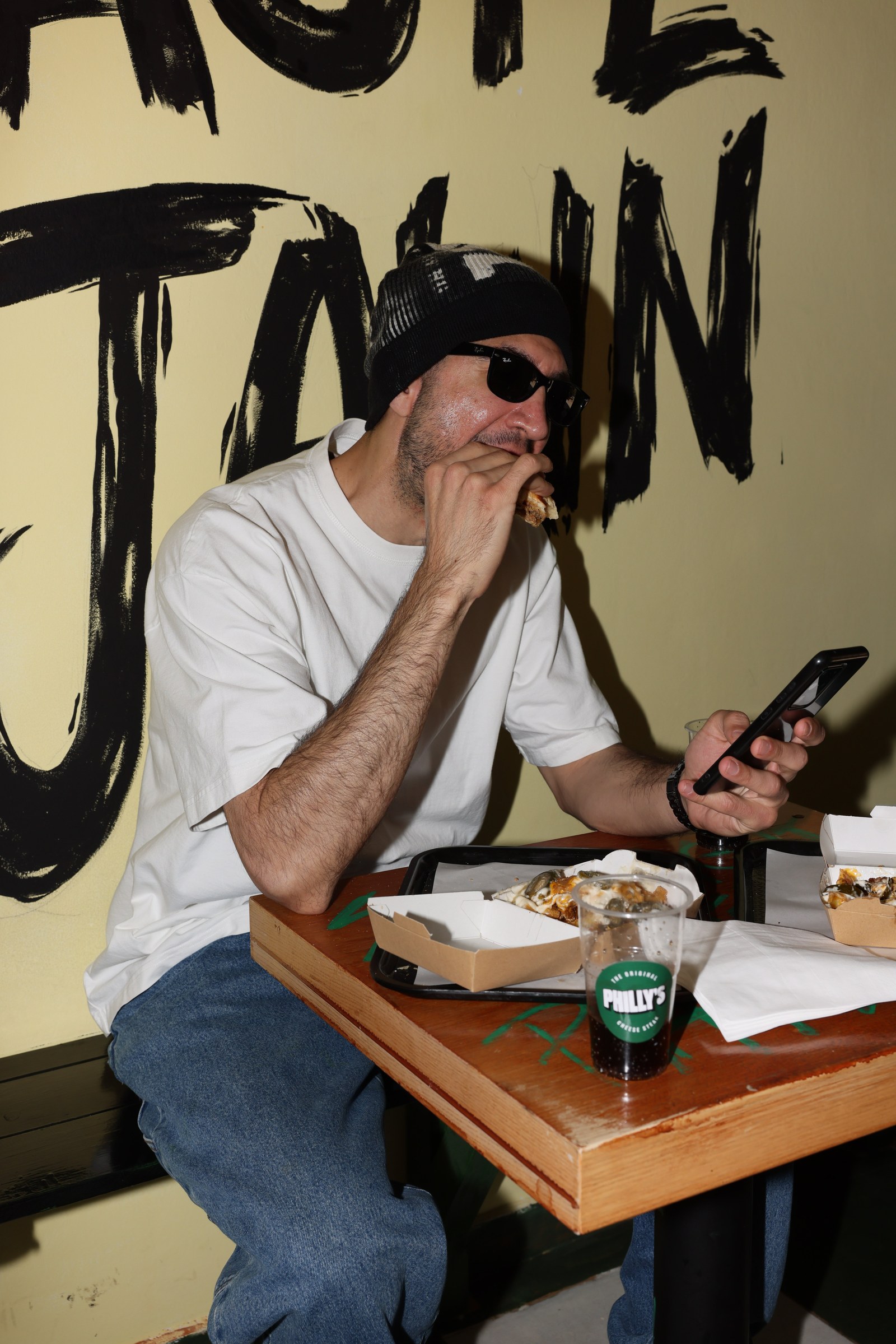 Guest in sunglasses eating a cheesesteak at Philly&rsquo;s