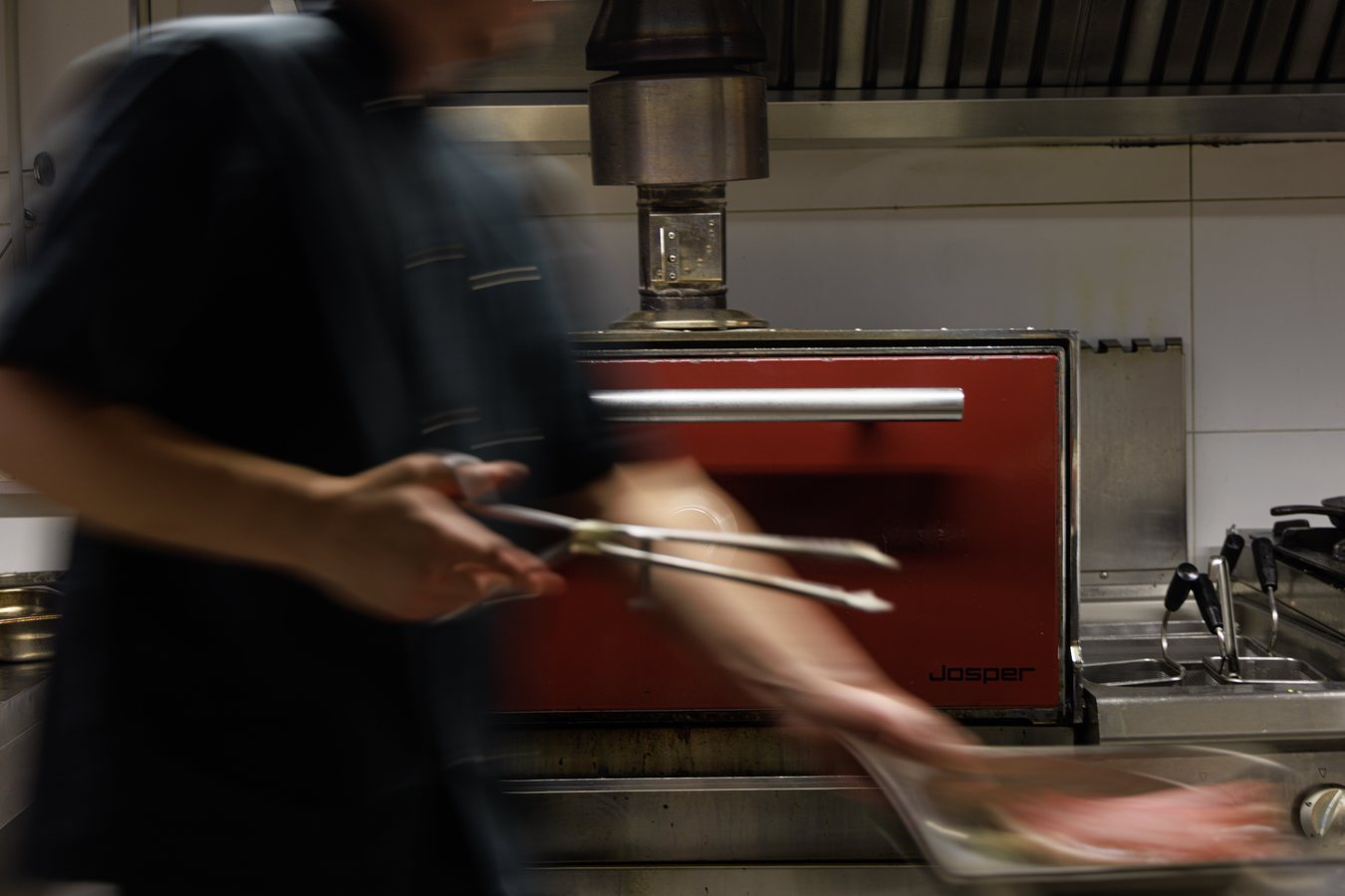 Cook moving fast in front of the red Josper charcoal oven