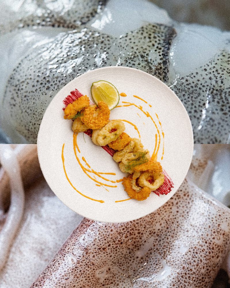 Fried calamari with lime and pepper sauce on a white plate