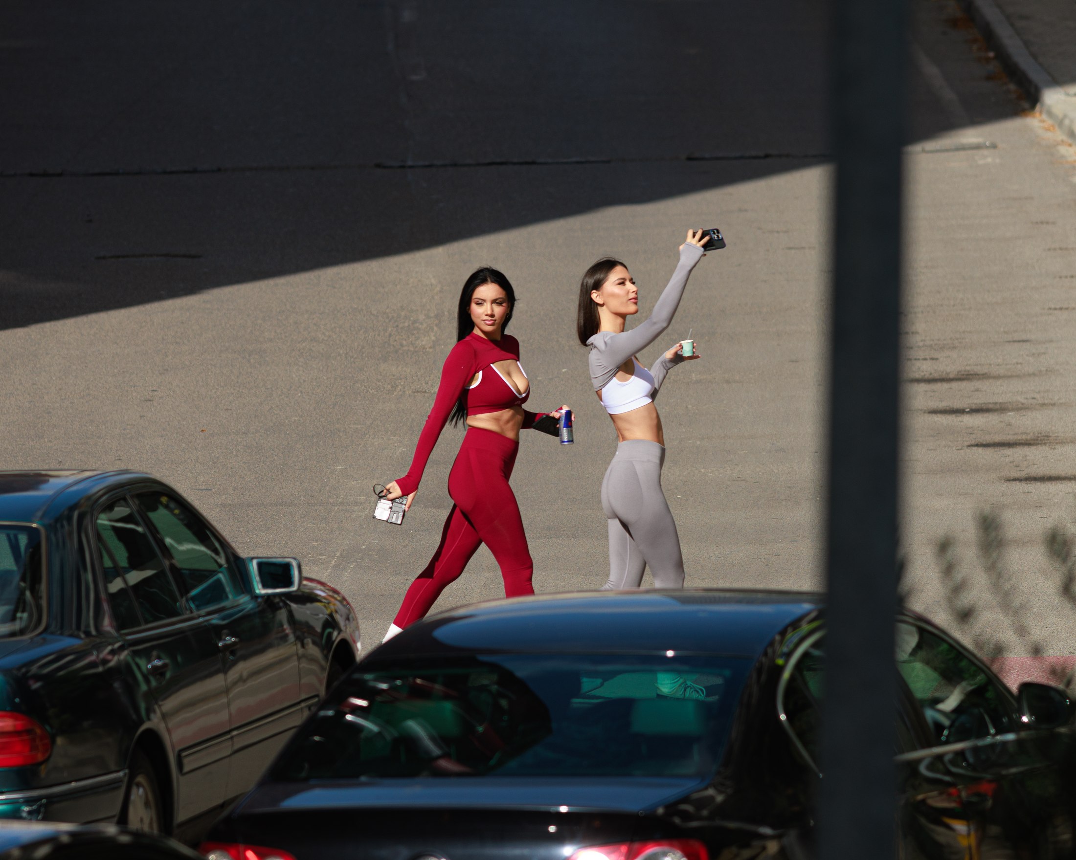 Two models in red and grey LULU sets walking between parked cars in the sun