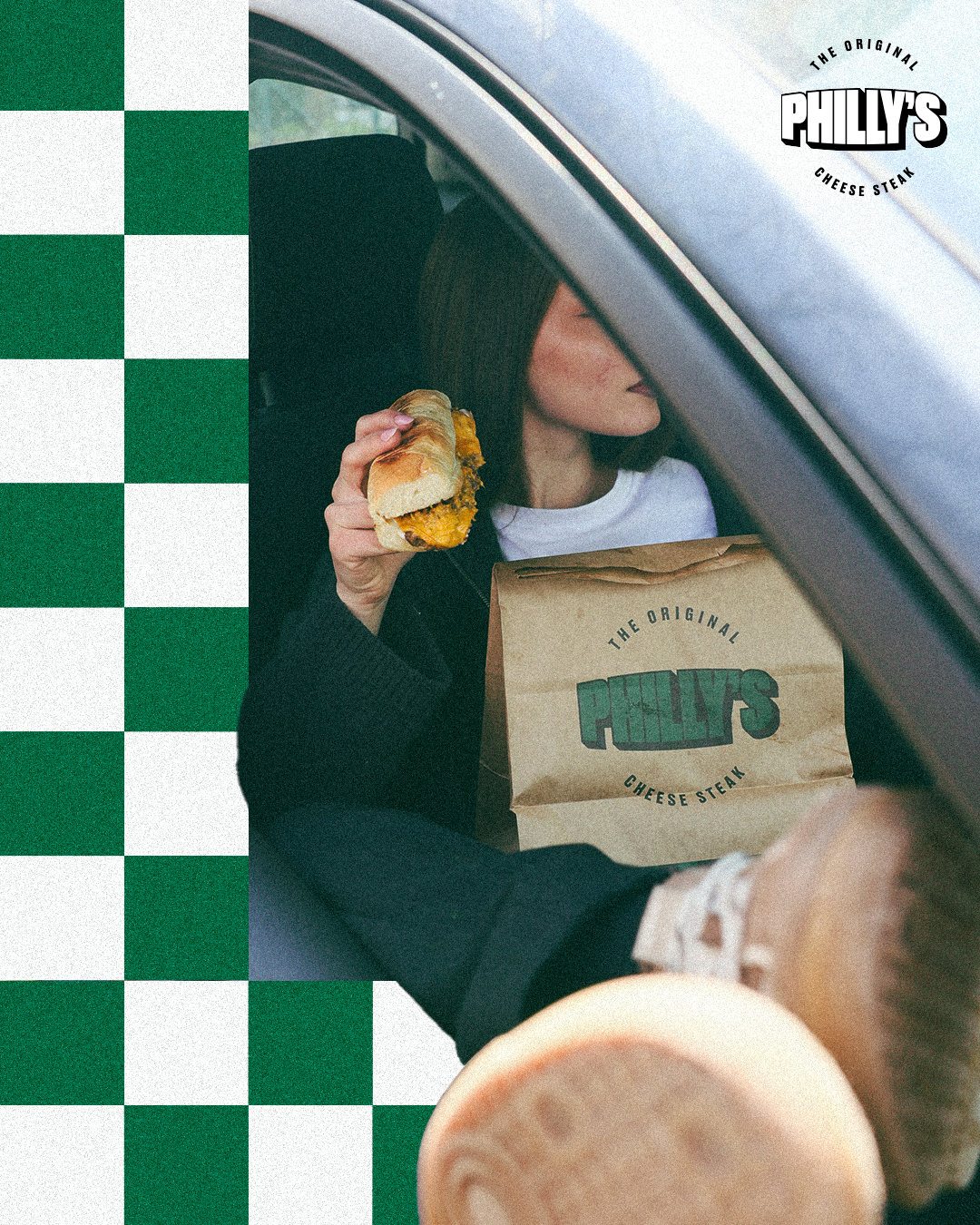 Cheesesteak in the car, framed by the green checkerboard