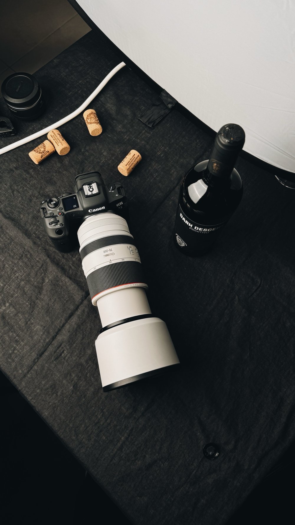 Canon camera and 70-200 lens beside a wine bottle on the set