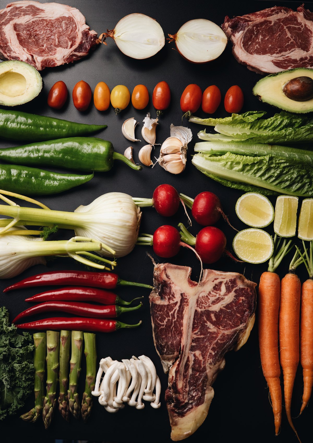 Flat lay of steaks, T-bone and fresh vegetables on black