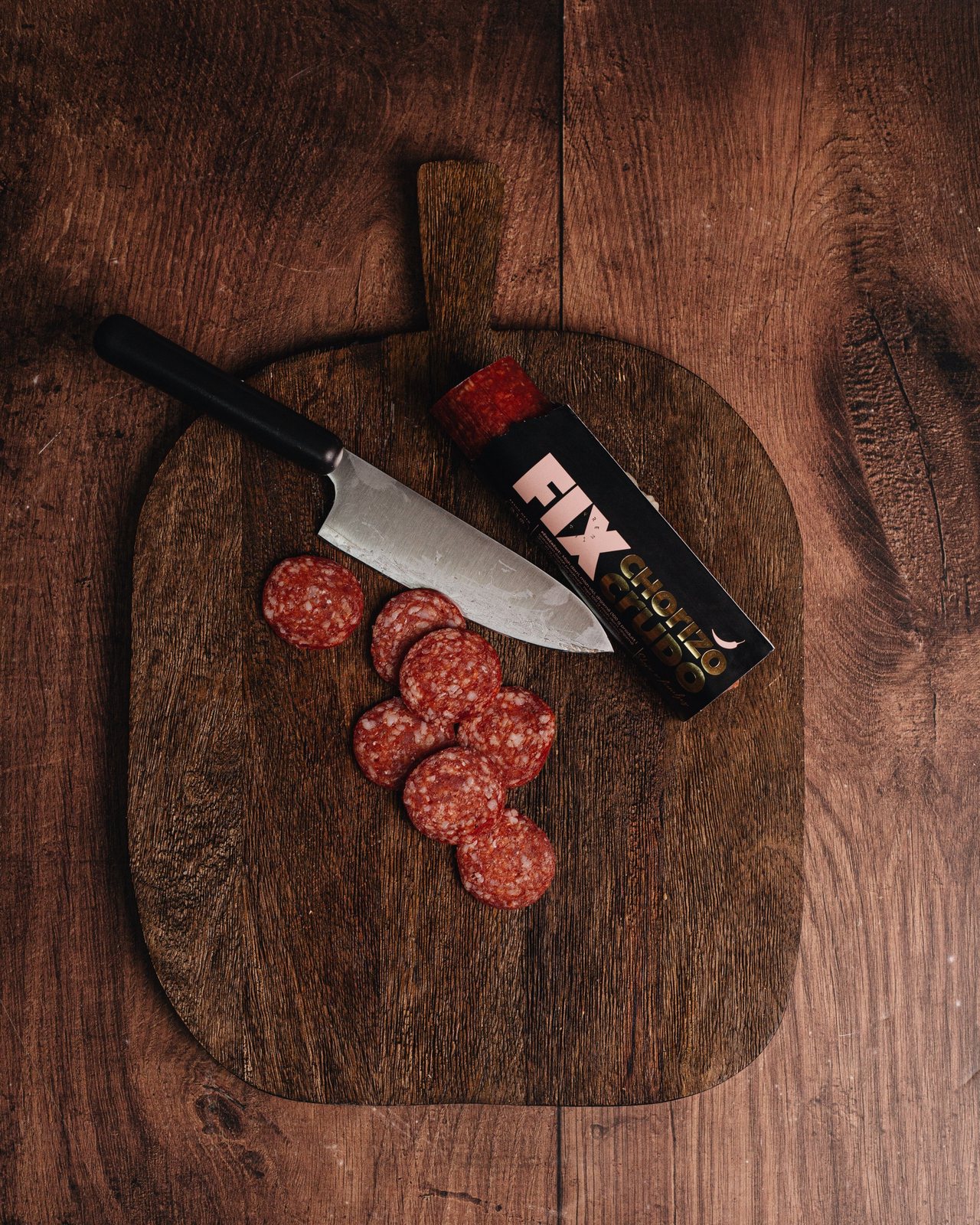 FIX Chorizo Crudo sliced on a wooden board with a knife