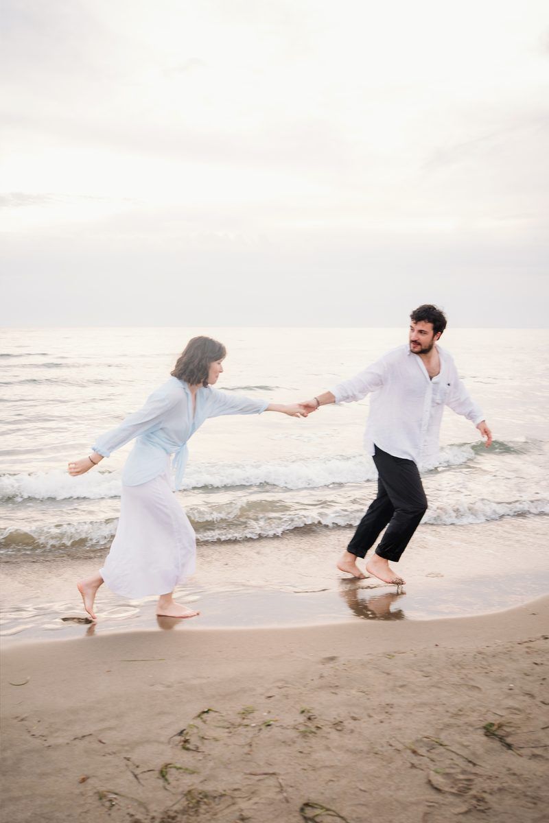 Couple running hand in hand along the shoreline