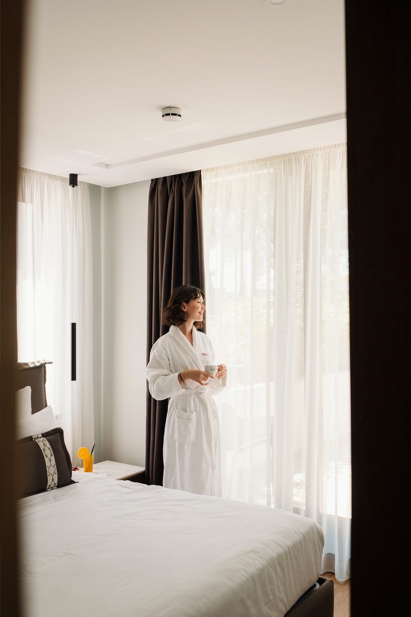 Guest in a Mövenpick robe with coffee by the window