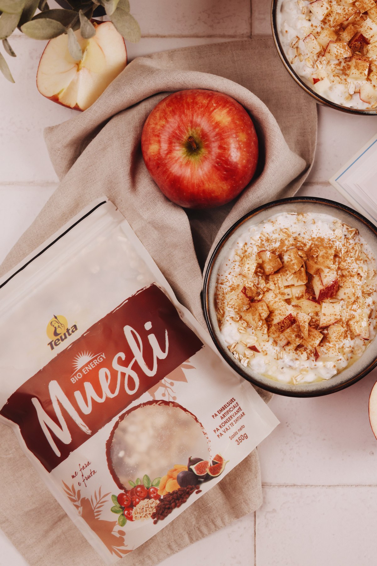 Teuta Muesli pack beside bowls of overnight muesli with apple and cinnamon