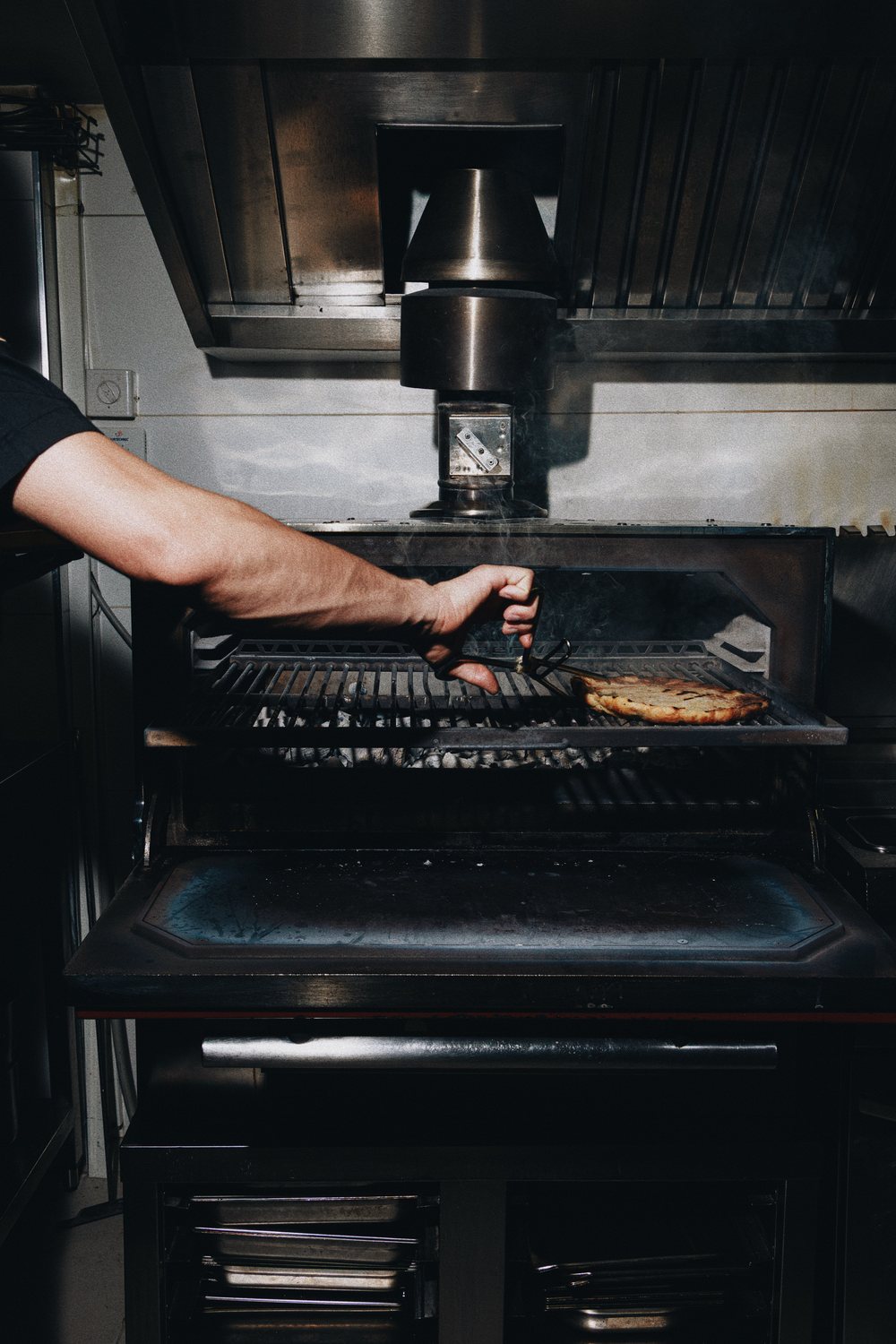 A cook turning flatbread on the charcoal grill