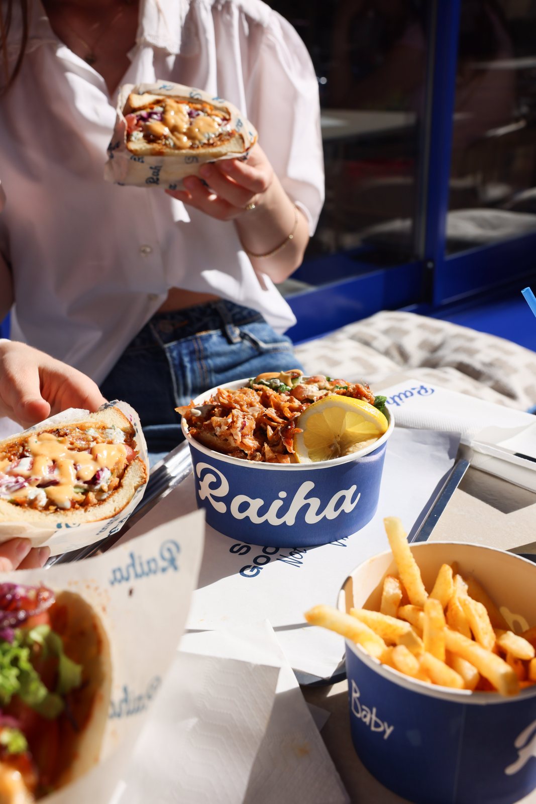 Friends sharing Raiha kebabs, bowl and fries in the sun