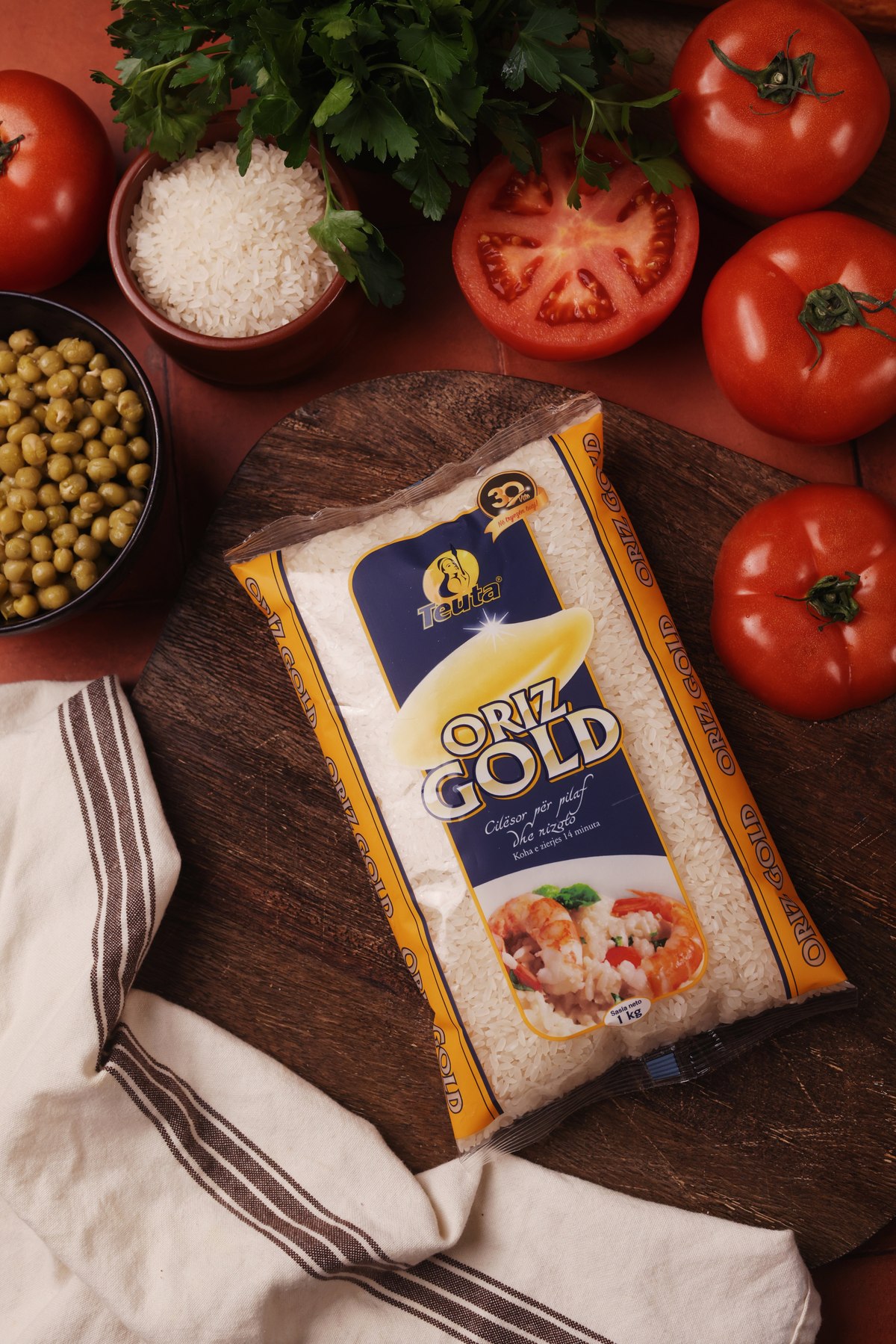 Teuta Oriz Gold rice pack on a board with tomatoes, peas and parsley