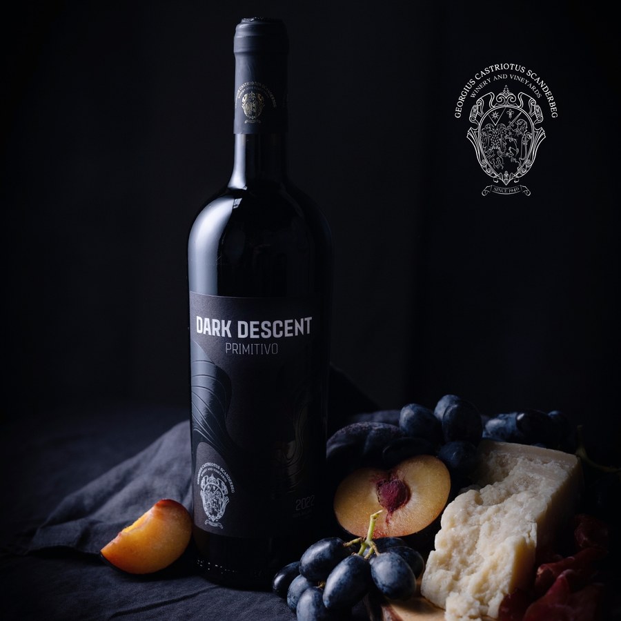Dark Descent Primitivo bottle with plums, grapes and cheese