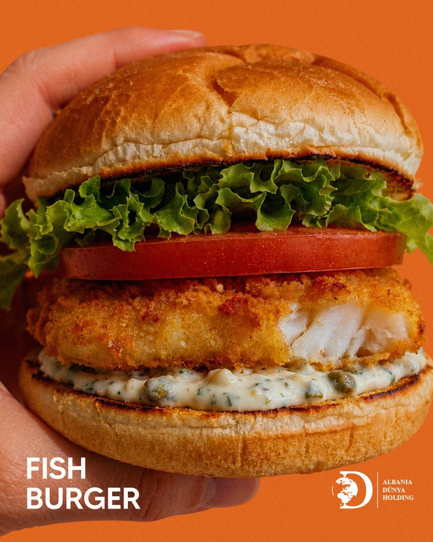 Fish burger held in hand against orange