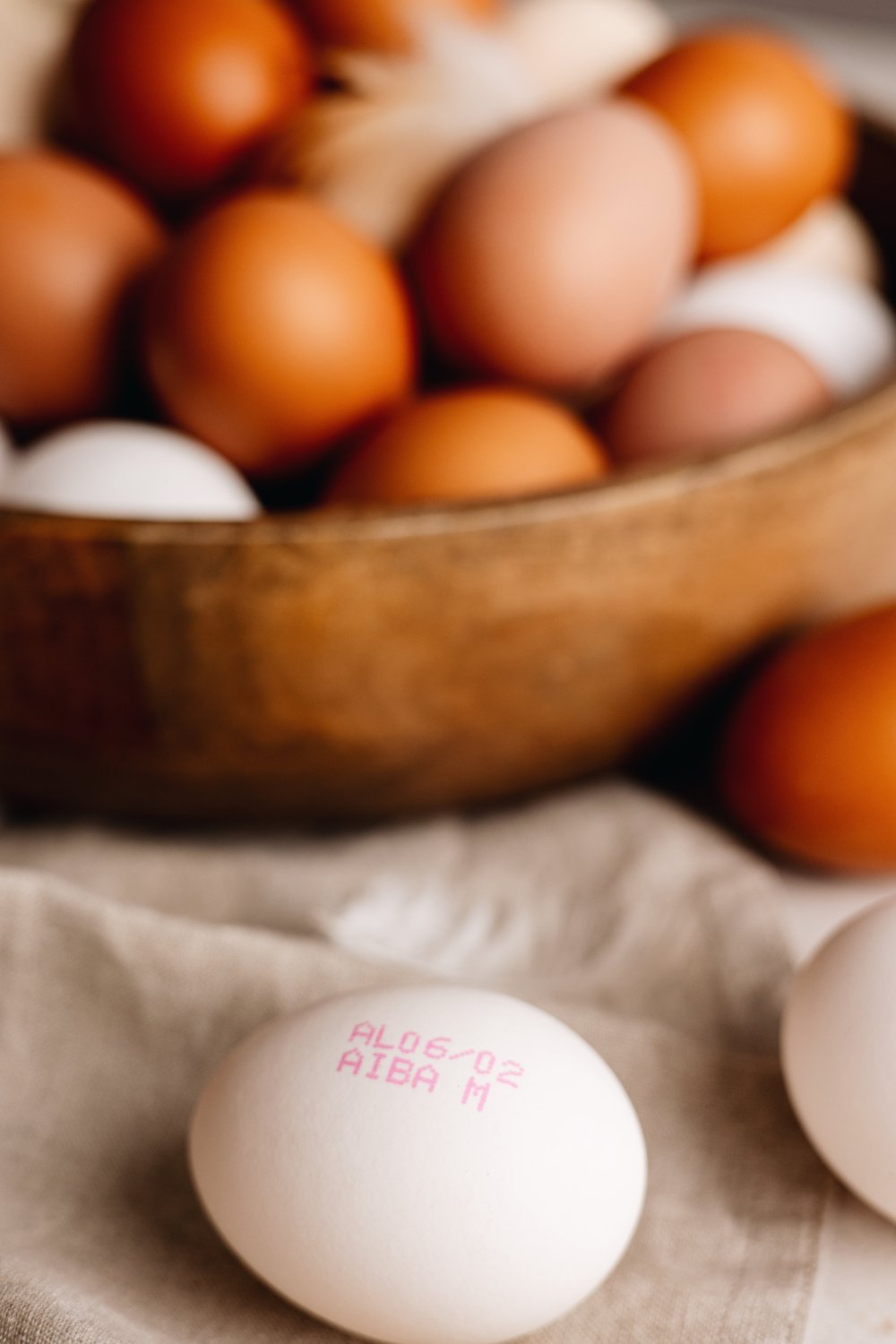 Close-up of an AIBA stamped egg in front of a bowl of brown eggs