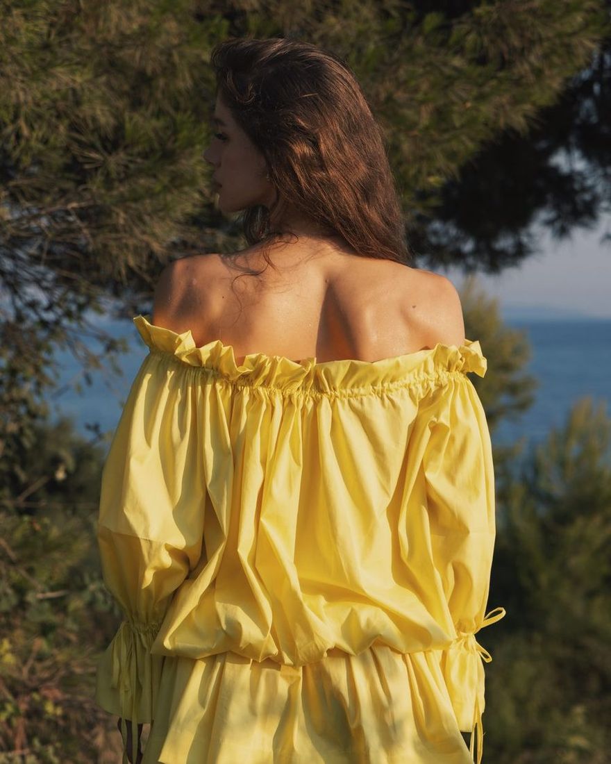 Back of the yellow TIERR off-shoulder top with the sea behind