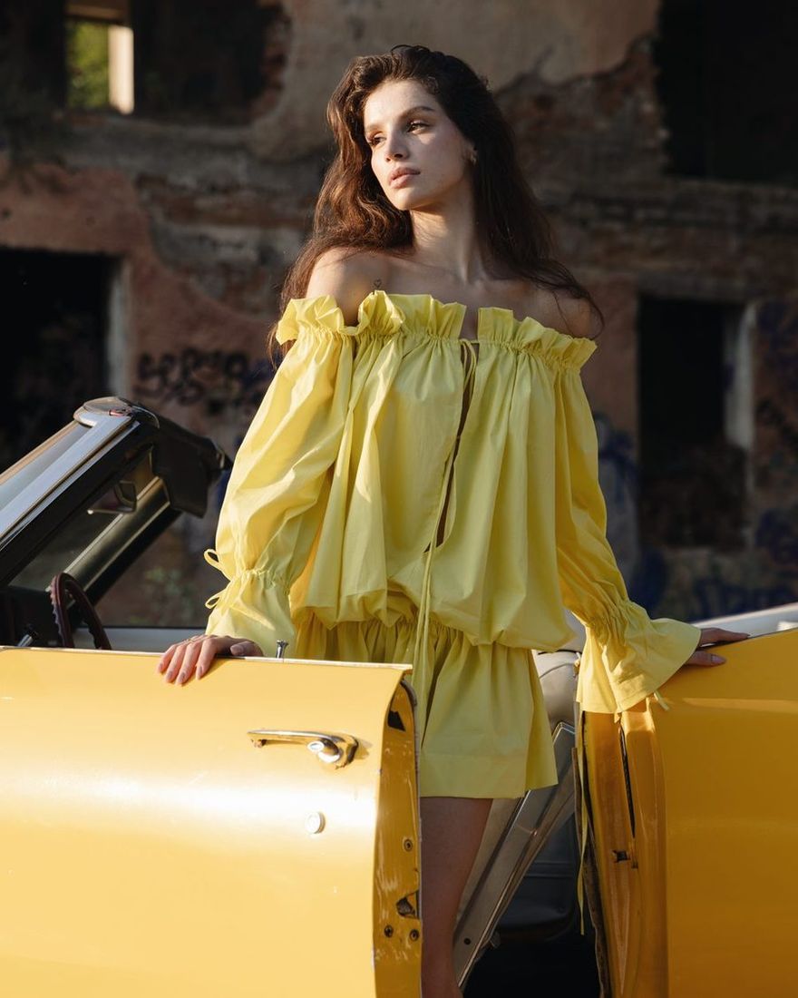 Model in a yellow TIERR off-shoulder set between the doors of a yellow convertible