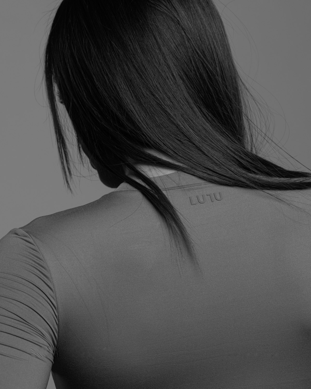 Black and white close-up of the LULU logo on the back of a grey top