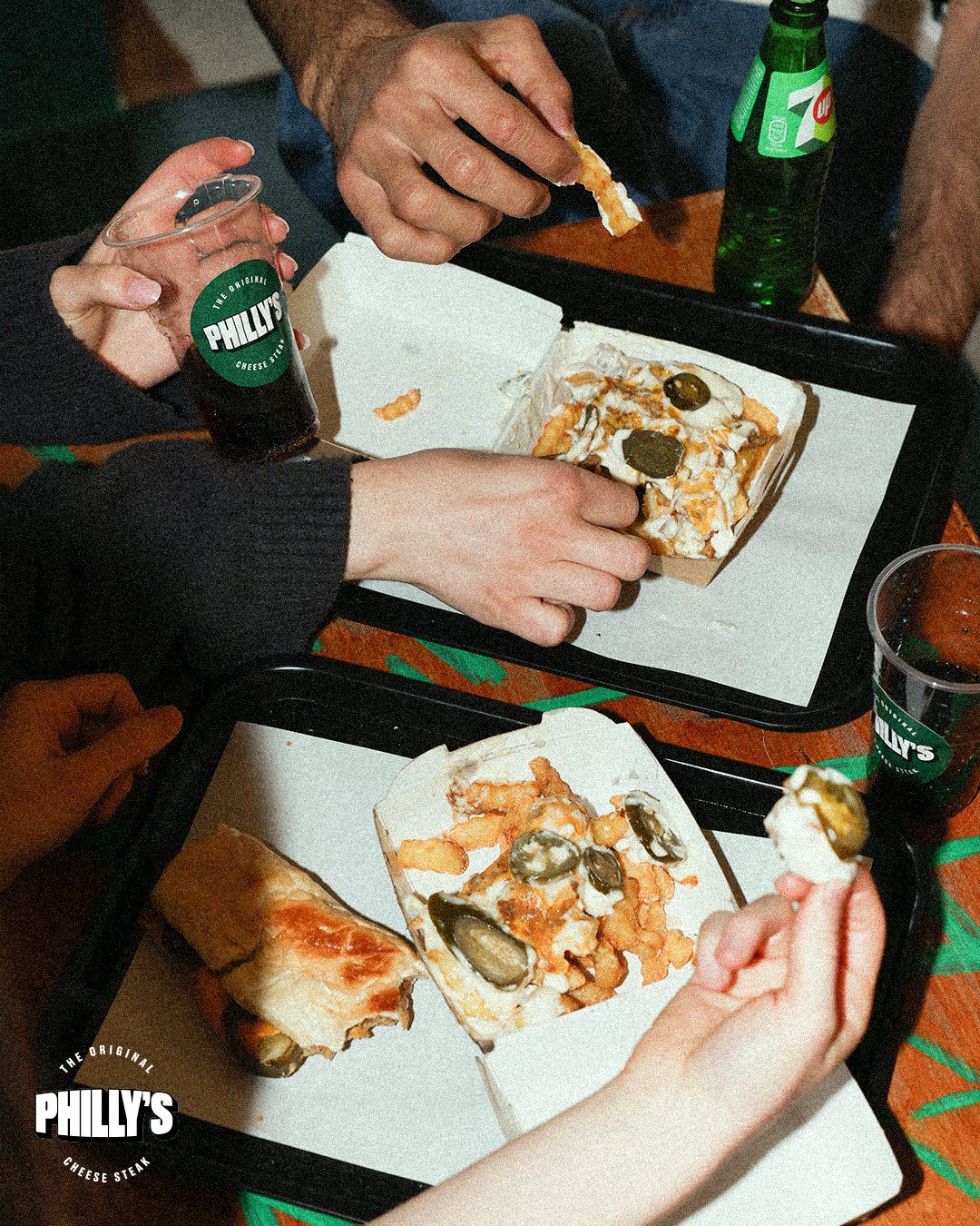 Friends sharing cheesesteaks and loaded fries on trays