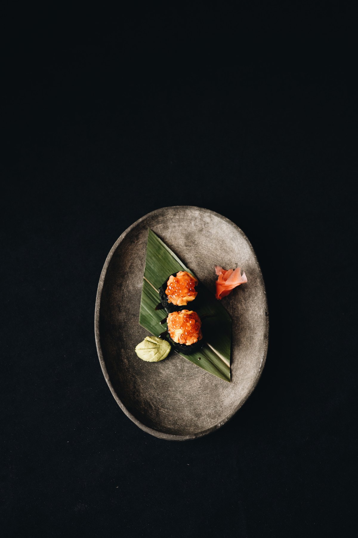 Two gunkan sushi with salmon roe on a stone plate