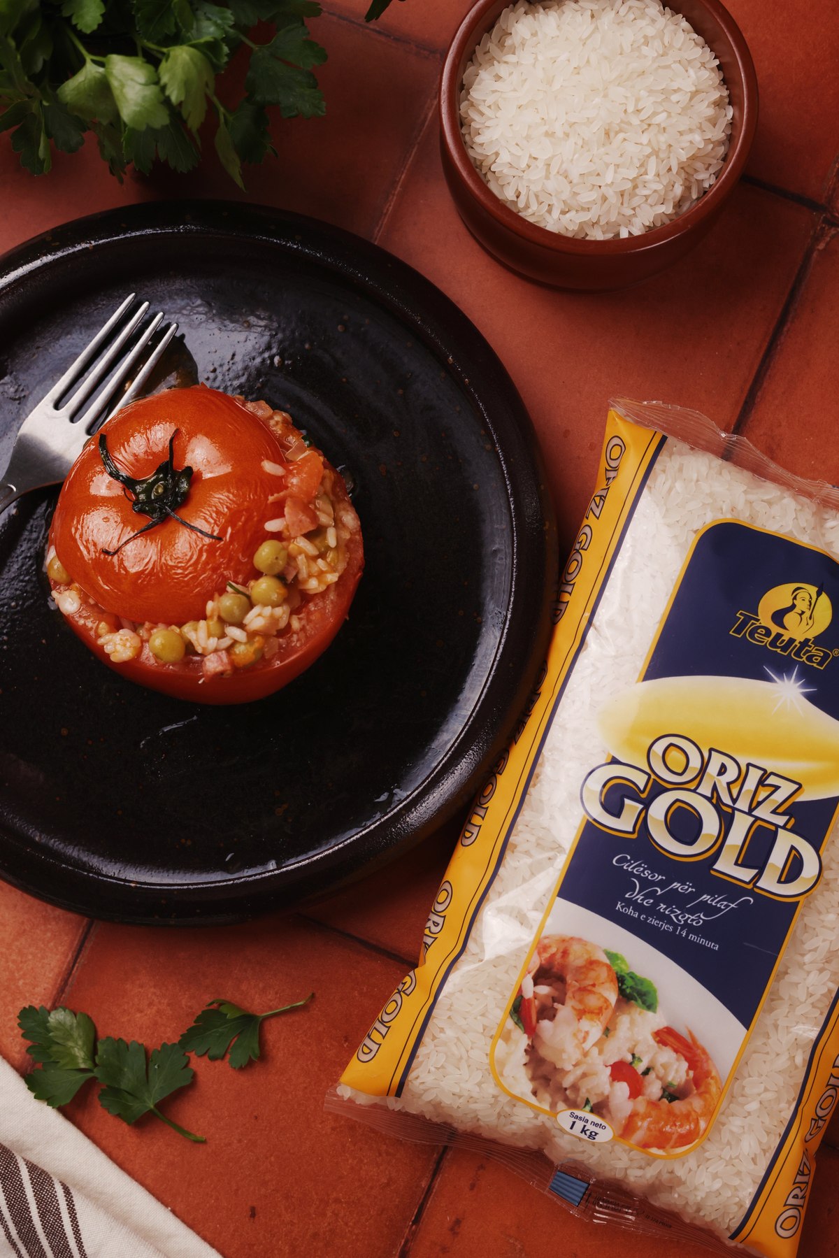 Tomato stuffed with rice and peas beside a Teuta Oriz Gold pack