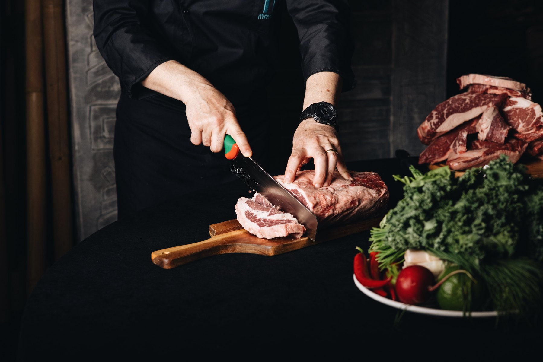 Chef slicing a ribeye roll on a wooden board