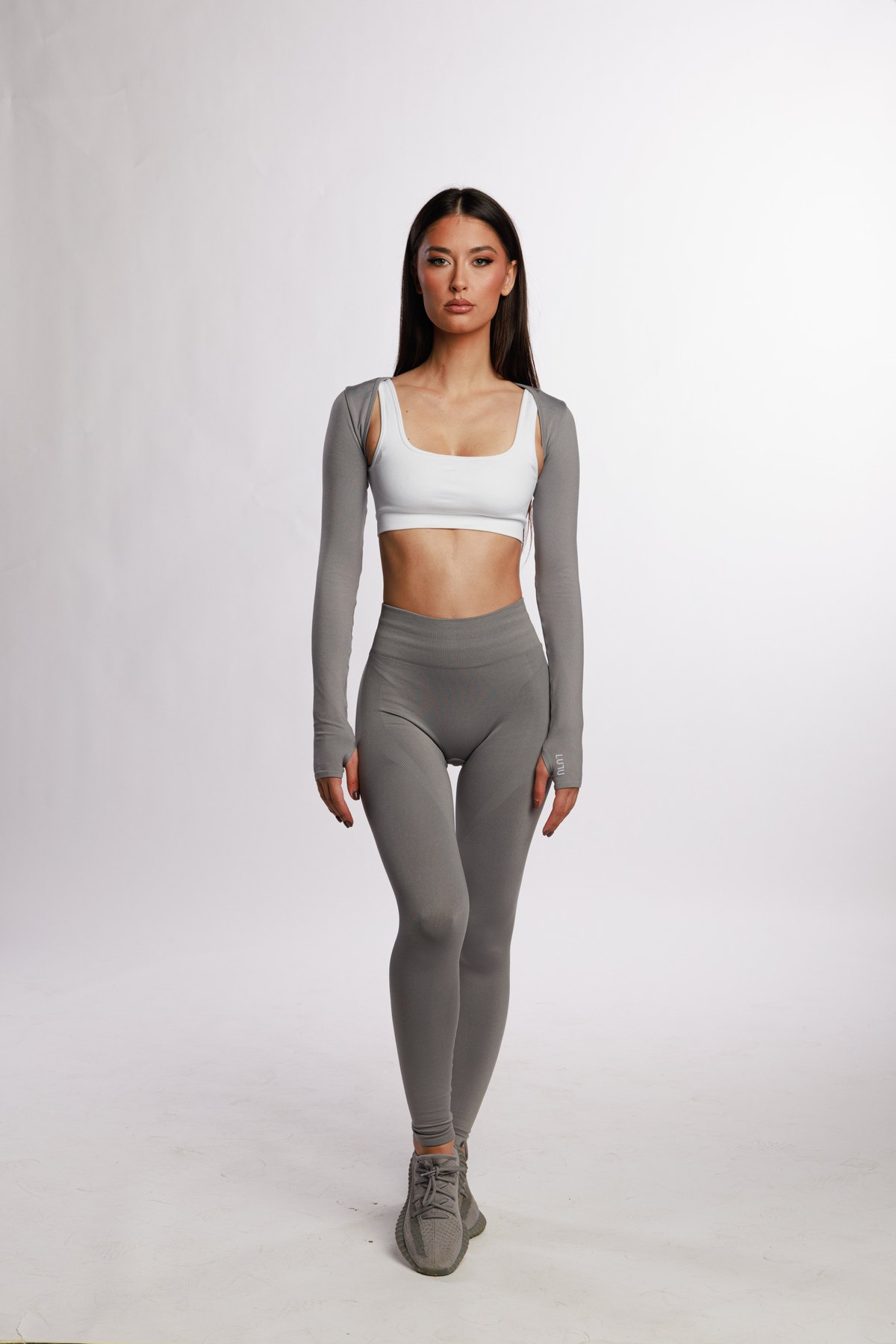 Model in a grey LULU shrug, white bra and grey leggings, full length