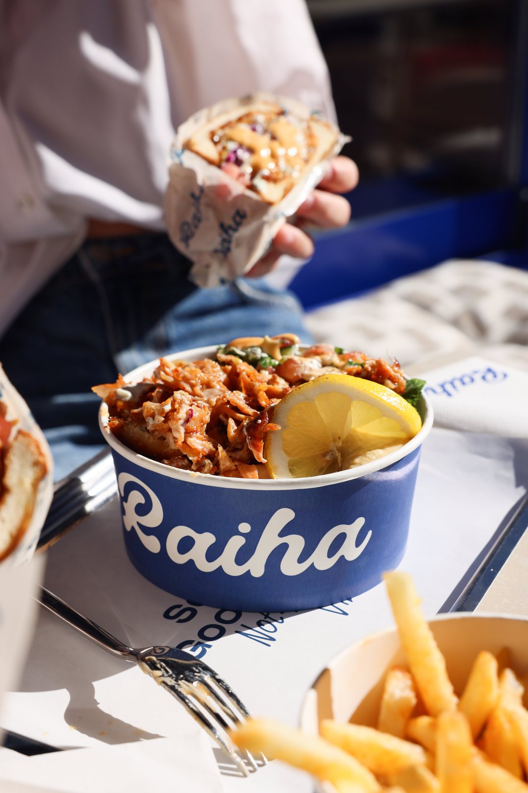Raiha bowl with lemon and a kebab in hand