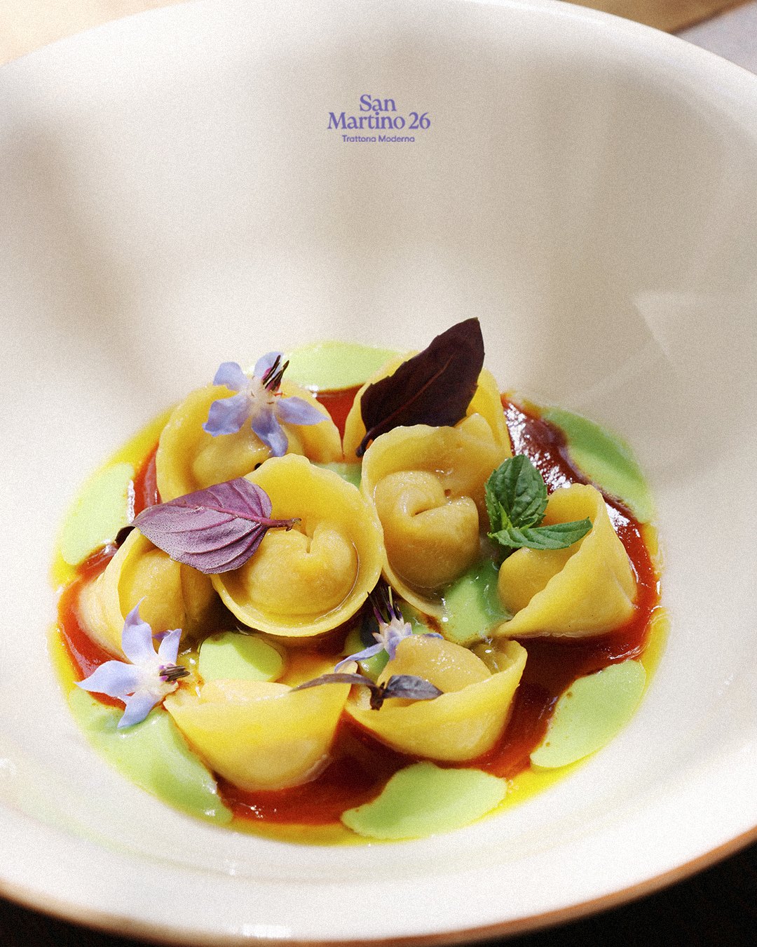 Tortellini with tomato sauce, pea cream and edible flowers