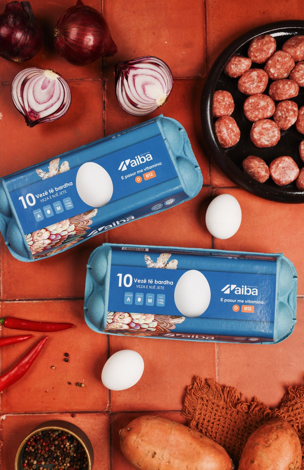 Two blue AIBA ten-egg cartons with onions, chillies and meatballs
