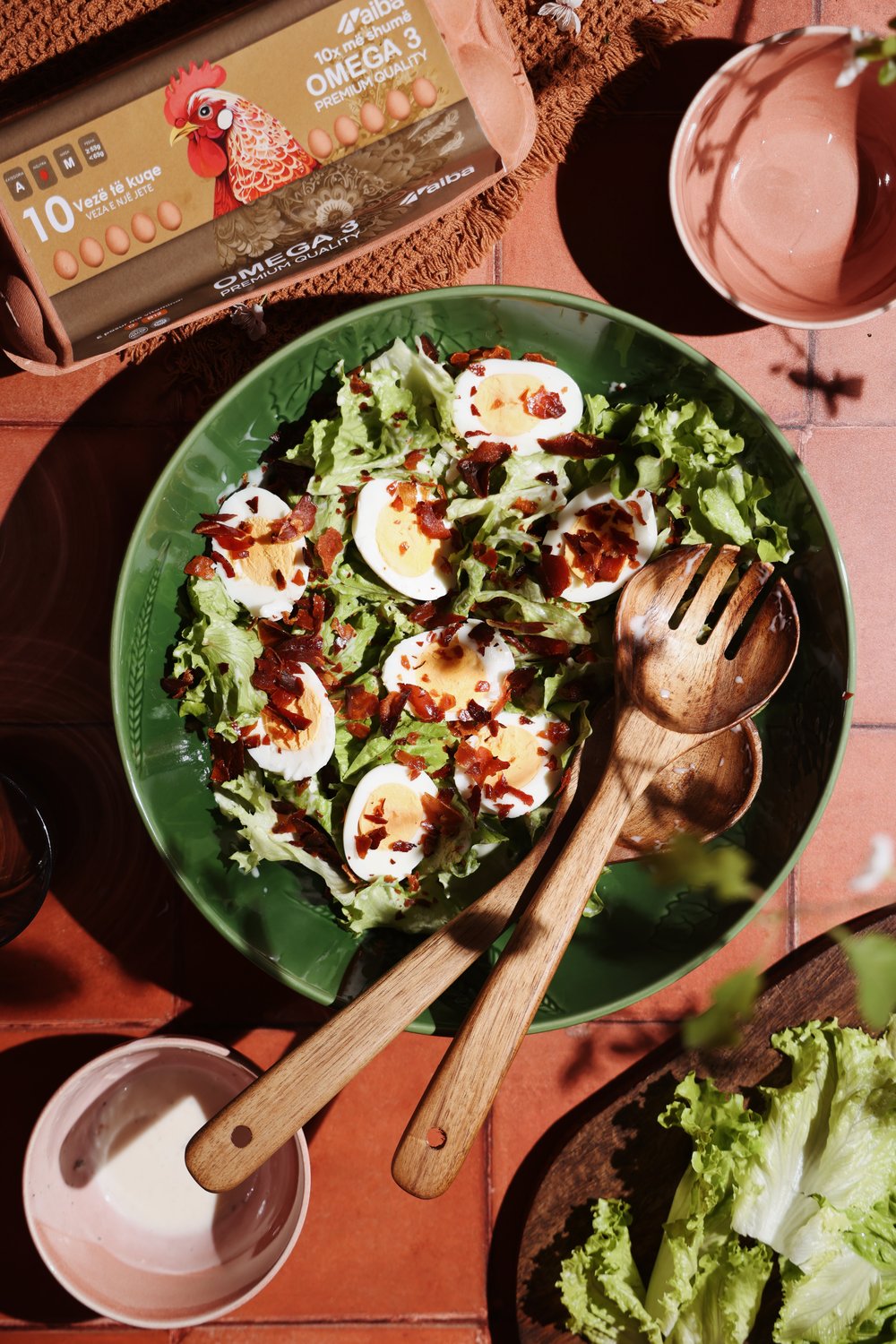 Green salad with boiled eggs and crisp bacon beside an AIBA Omega 3 carton