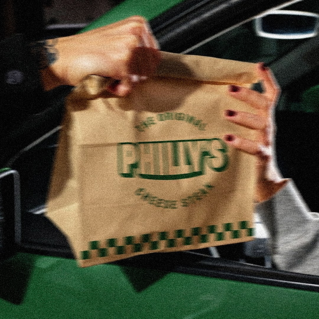 Philly&rsquo;s takeaway bag handed through a green car window