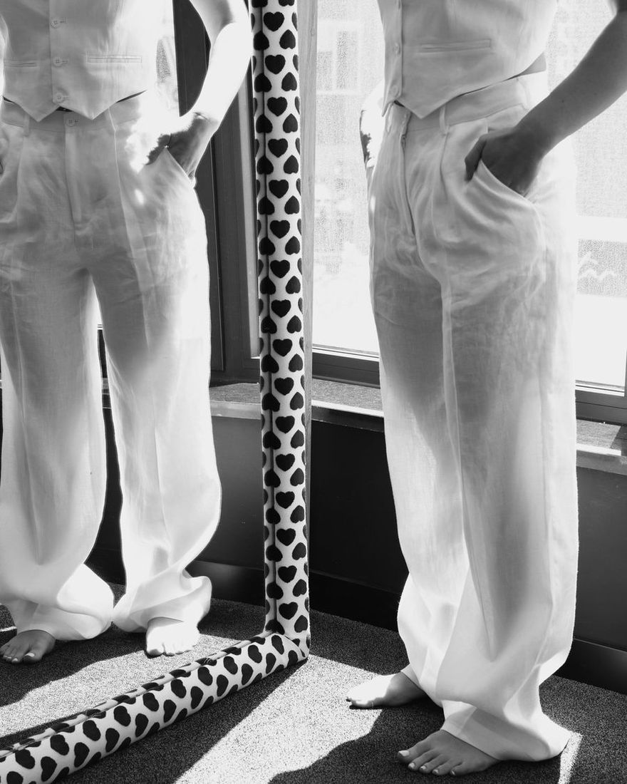 Black and white shot of white TIERR linen trousers beside a heart-print mirror