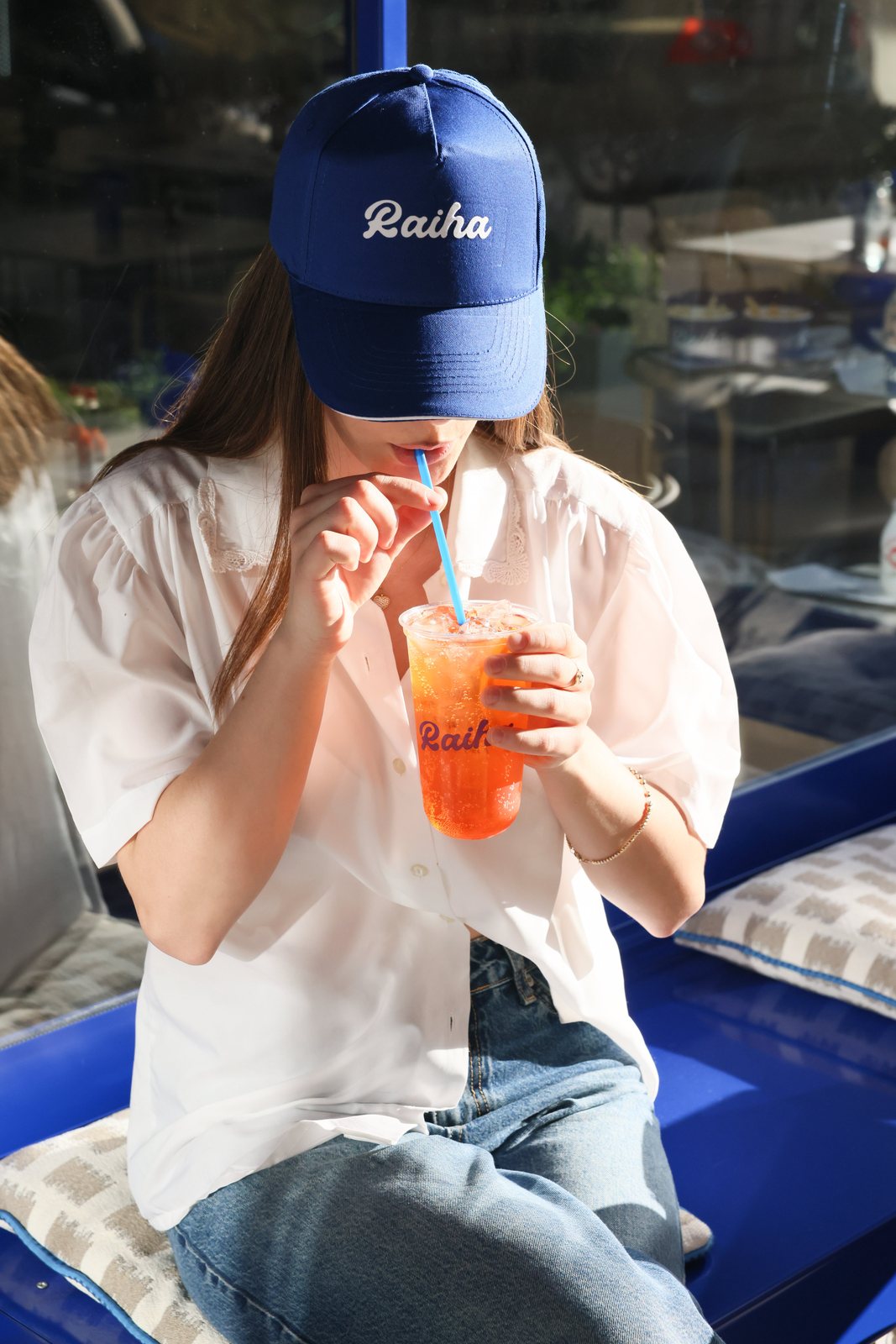 Woman in a Raiha cap sipping an orange soda