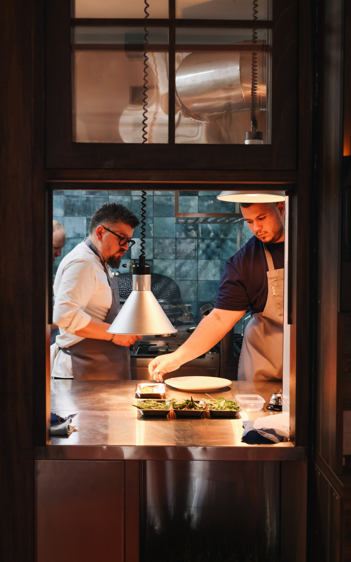 Chefs at the pass under warm heat lamps