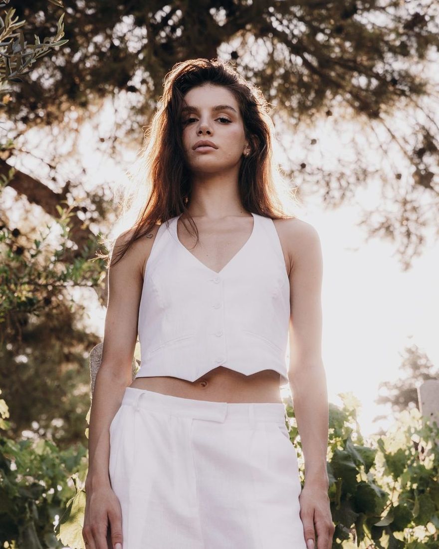 Model in a white TIERR halter waistcoat and trousers under a pine tree