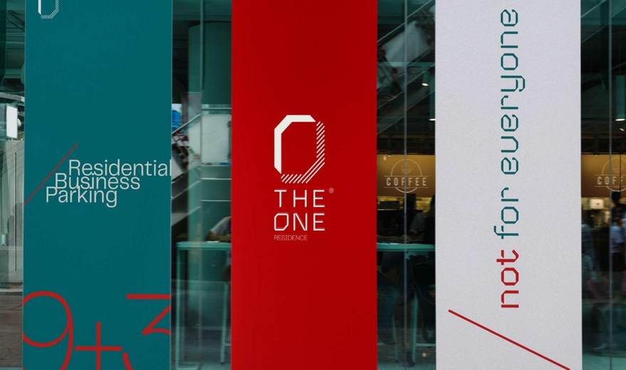 The One roll-up posters in teal, red and gypsum installed on a storefront window